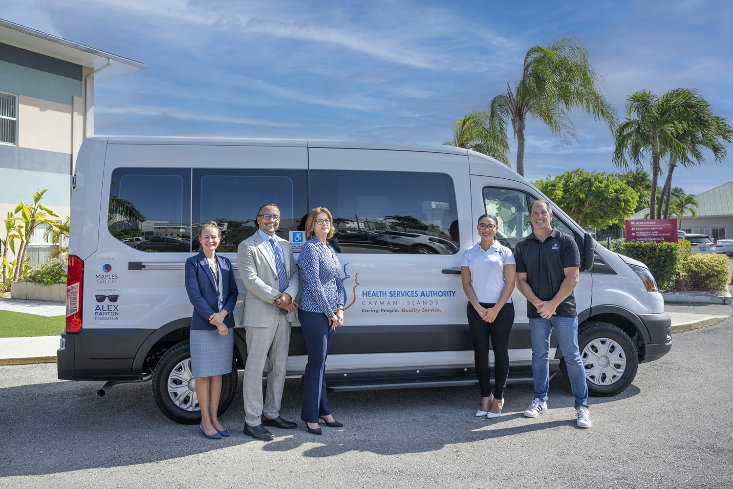 White van branded with Alex Panton Foundation, Health Services Authority and Maples Group logos parked in front of Alex's Place location. Representatives from HSA, Alex Panton Foundation and Maples Group stand in front of the van.